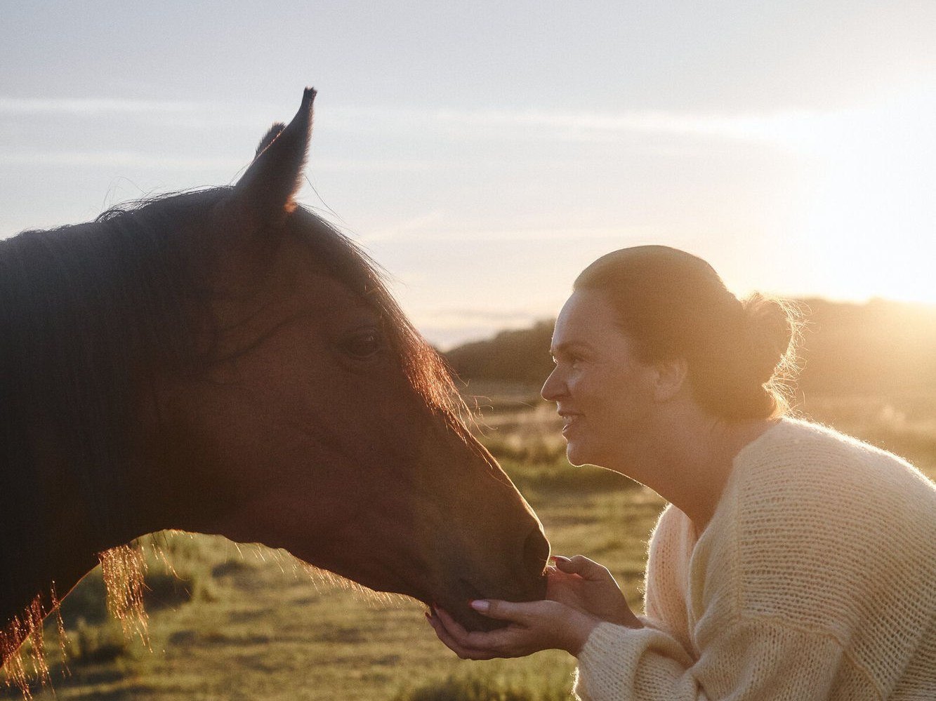 Kathrin Keiper begrüßt ihr Pferd in der Abendsonne